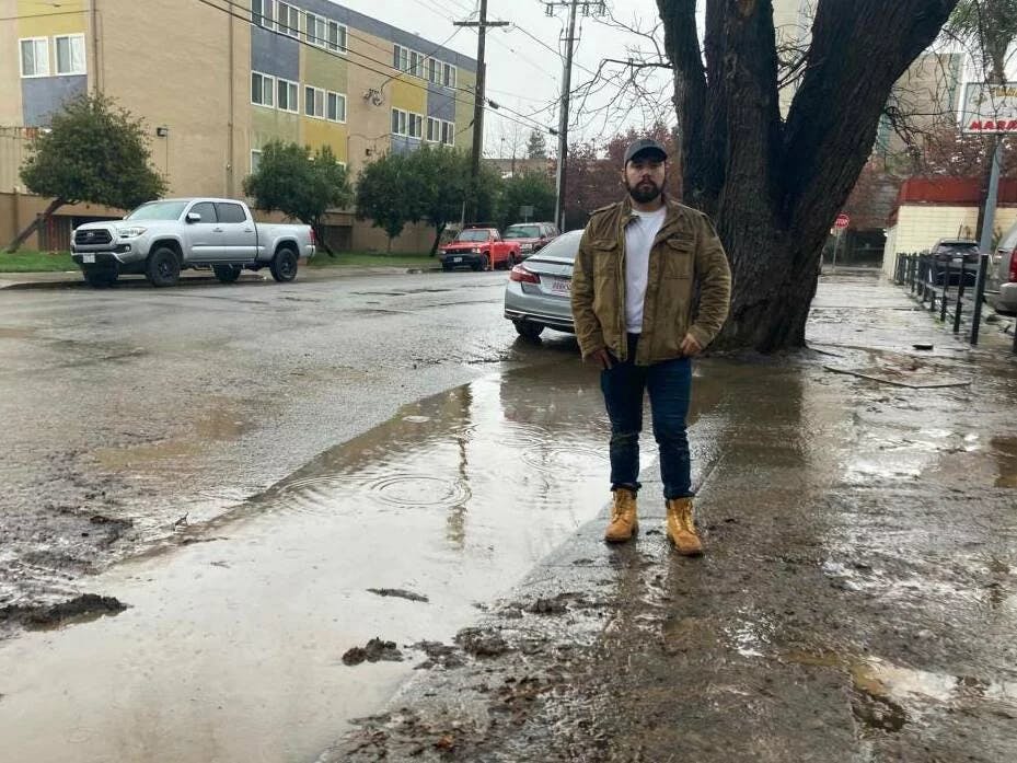 Antonio López standing next to floodwaters from a storm in January 2023